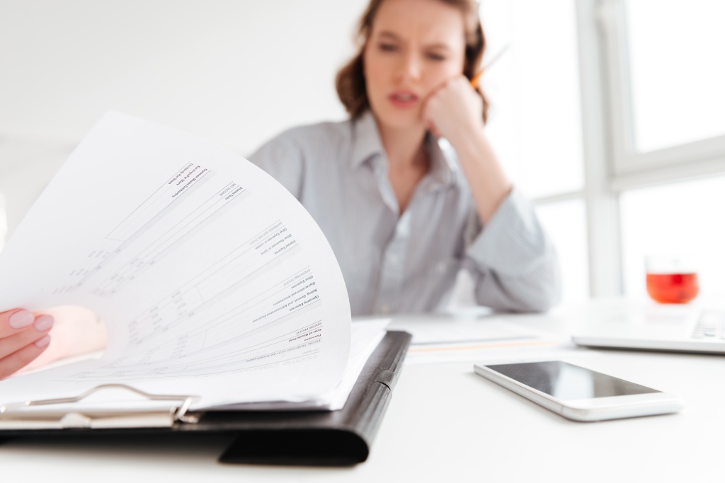 serious-brunette-woman-reading-papers-while-siting-workplace-light-aparment-selective-focus-document.jpg работник